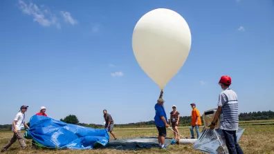 Plusieurs participants se préparent à lâcher un ballon-sonde sur un terrain vague Plusieurs participants se préparent à lâcher un ballon-sonde sur un terrain vague