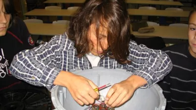 Une élève en train de poser un bloc de piles dans une bouée Une élève en train de poser un bloc de piles dans une bouée